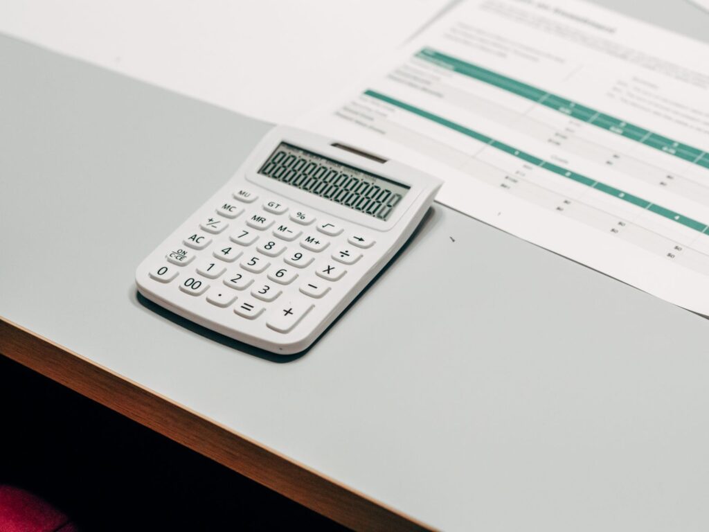 Calculator lying next to a financial spreadsheet on a white desk
