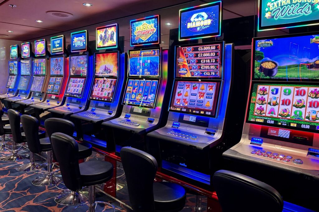 Row of brightly lit slot machines in an empty casino